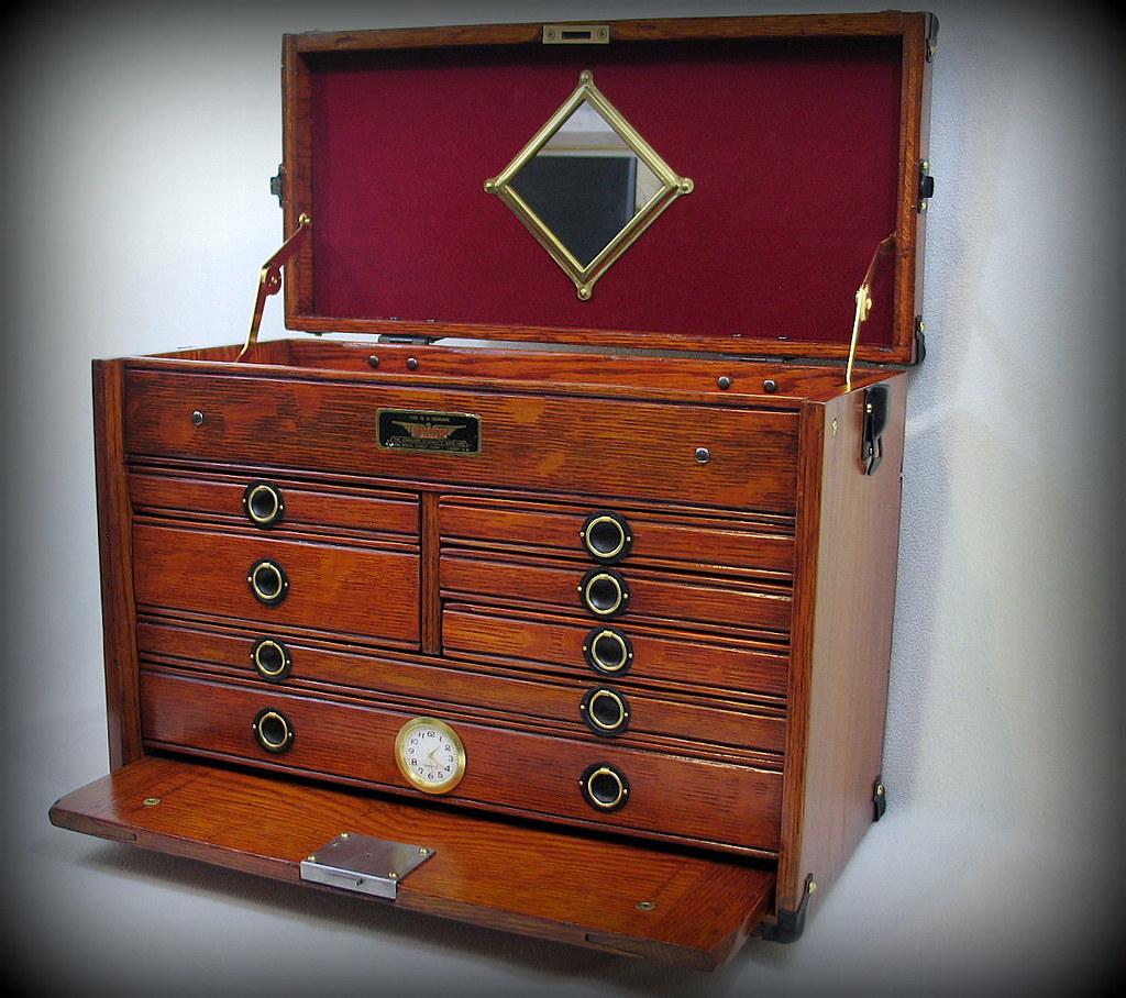 An open multi-drawer oak wood chest has a red felt-lined lid with a diamond mirror and clock. — illustrating “An every day lip look” on Florence and Mary