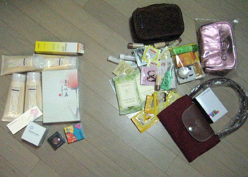 Skincare samples, boxed cosmetics, and small makeup bags are scattered across a light wood floor. — illustrating “August Favourite // Dove Purely Pampering Nourishing Lotion” on Florence and Mary