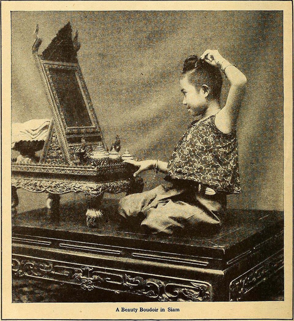 A sepia historical photo shows a child in traditional Siamese dress grooming before an ornately carved mirror. — illustrating “Beauty Wish List February 2014” on Florence and Mary