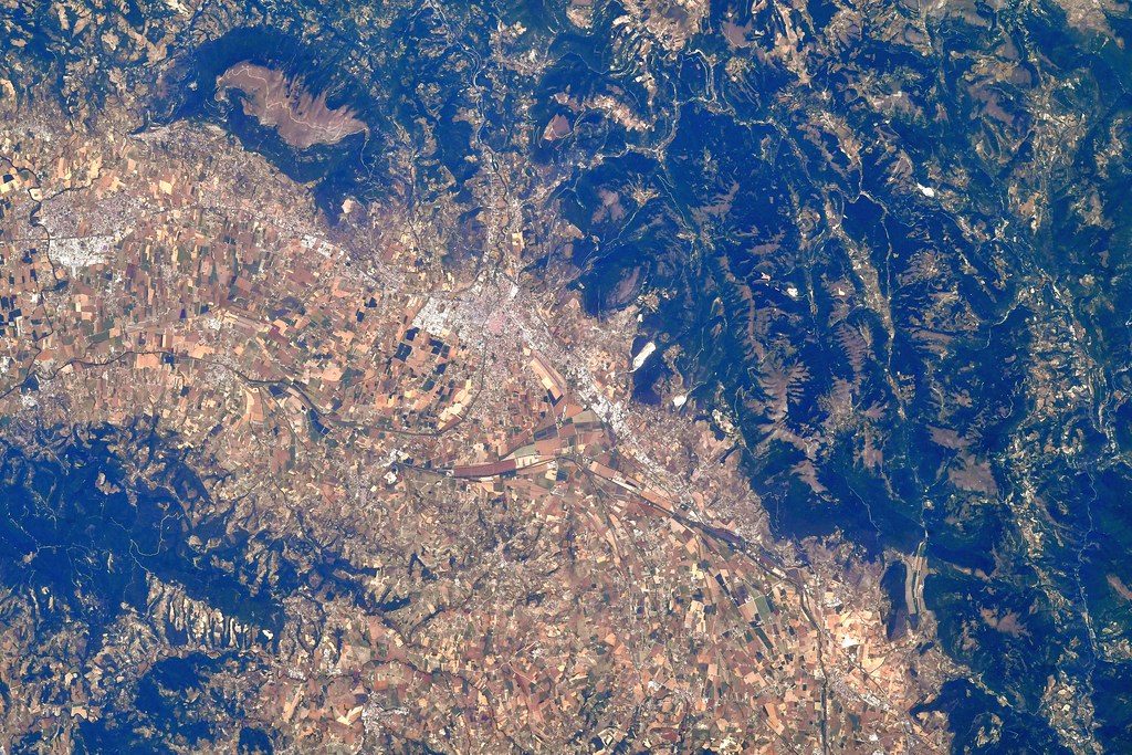 An aerial view shows brown agricultural fields nestled between dark green mountains and nearby urban areas. — illustrating “Bloglovin from my BFF” on Florence and Mary