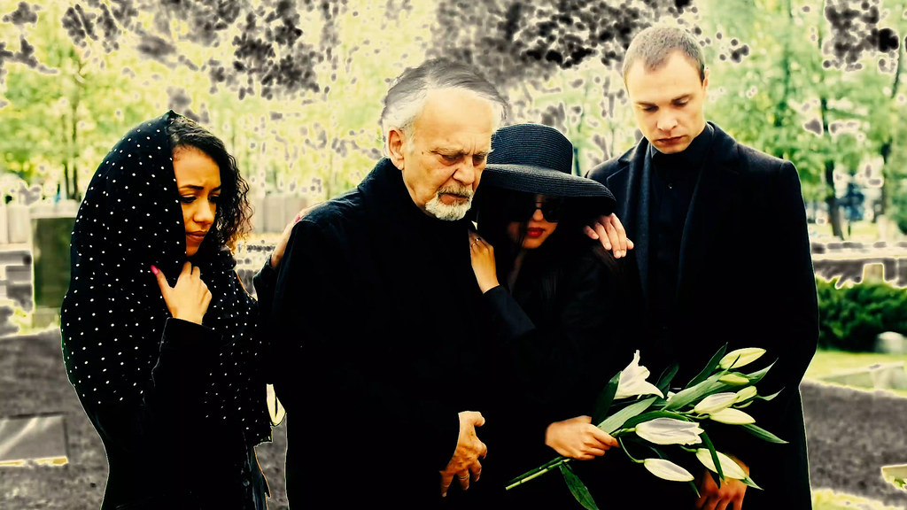 Four somber people in black mourning clothes stand in a green cemetery, one woman holding white lilies. — illustrating “Chanel Avant-Première de Chanel Collection” on Florence and Mary