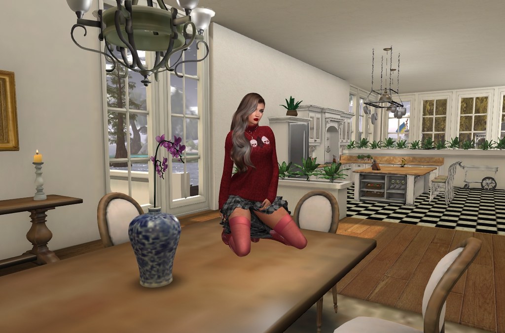 A female avatar in a red skull-patterned sweater and pink stockings kneels on a wooden dining table. — illustrating “Come Dine With Me” on Florence and Mary
