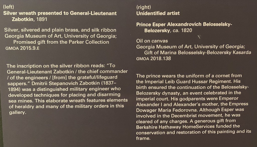 A dark gray museum placard with white text describes a silver wreath gift and a historical portrait painting. — illustrating “Didn’t we do well!” on Florence and Mary