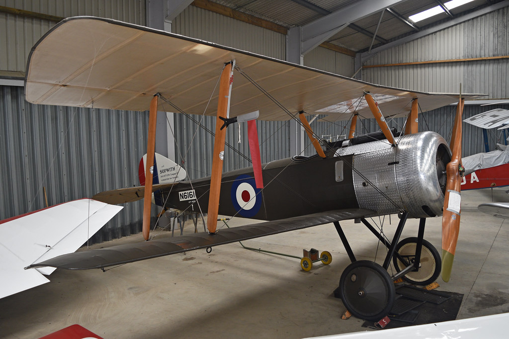 A vintage Sopwith biplane with silver engine cowling and tan wings sits inside a corrugated metal hangar. — illustrating “February 2015 Beauty Favourites” on Florence and Mary