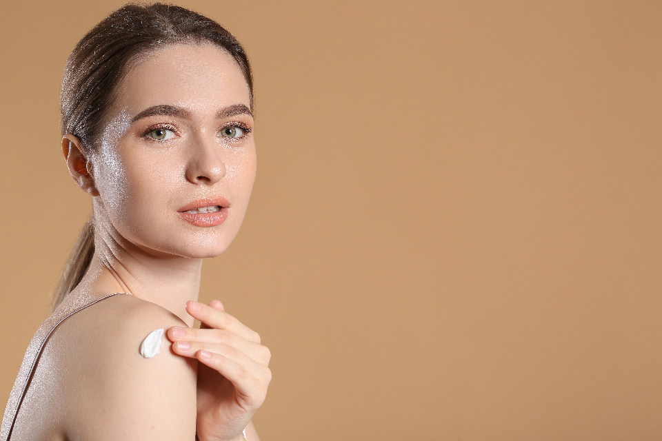 A glitter-covered woman applies a dab of white cream to her bare shoulder against a solid tan backdrop. — illustrating “Fruity Skincare Favourites” on Florence and Mary