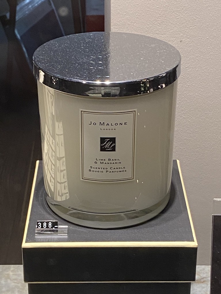 A large cream Jo Malone scented candle with a shiny silver lid rests on a black display pedestal. — illustrating “Jo Malone London” on Florence and Mary
