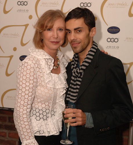 A woman in a ruffled white eyelet blouse and a man with a striped scarf pose before a logo backdrop. — illustrating “June Empties | Haircare” on Florence and Mary