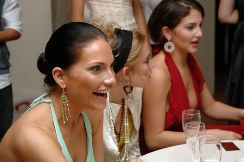 Three women in mint green and red formal dresses laugh at a table with champagne flutes at an event. — illustrating “L'Oreal Vs Garnier Eye Make Up Remover Battle” on Florence and Mary