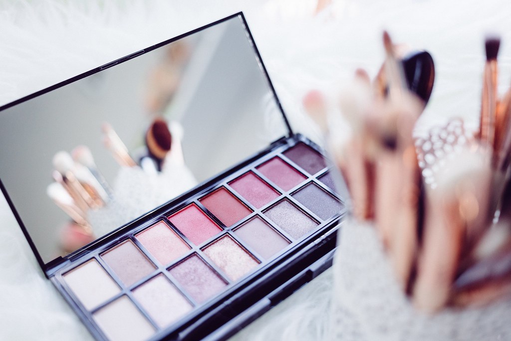 An open pink and neutral eyeshadow palette rests on white fluff beside a jar of makeup brushes. — illustrating “Make Up Brush Storage from IKEA” on Florence and Mary
