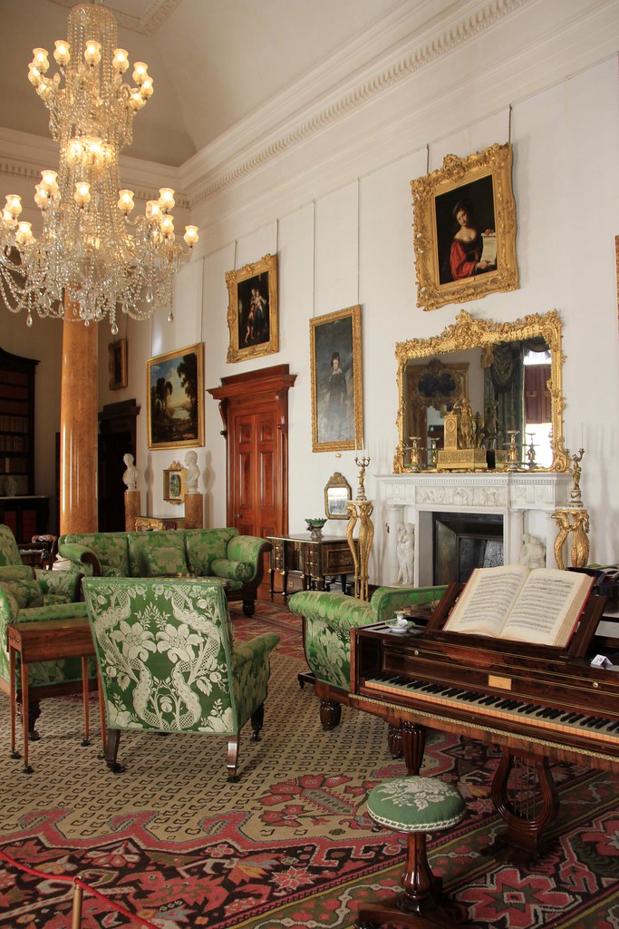 An ornate drawing room shows green floral sofas, a piano with sheet music, and gold-framed wall paintings. — illustrating “March 2014 Empties” on Florence and Mary