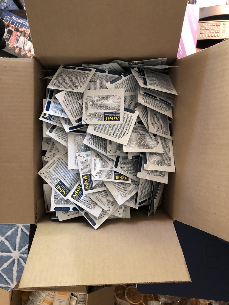 An open cardboard box is filled with numerous individual white and blue Advil medication packets from above. — illustrating “My Hangover Kit” on Florence and Mary