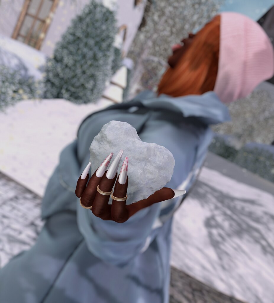 Hands with long pointed nails and gold rings hold a heart-shaped snowball outdoors in snow. — illustrating “Nails Inc Manicure” on Florence and Mary