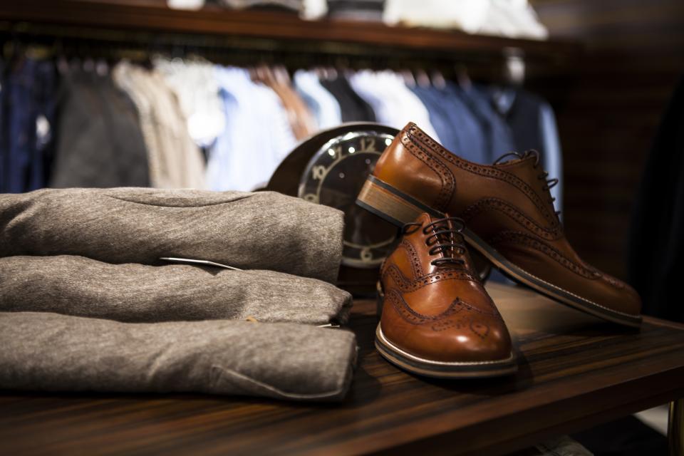 Tan leather brogue shoes sit on polished dark wood beside a stack of folded grey clothing. — illustrating “OOTD: Family Day” on Florence and Mary