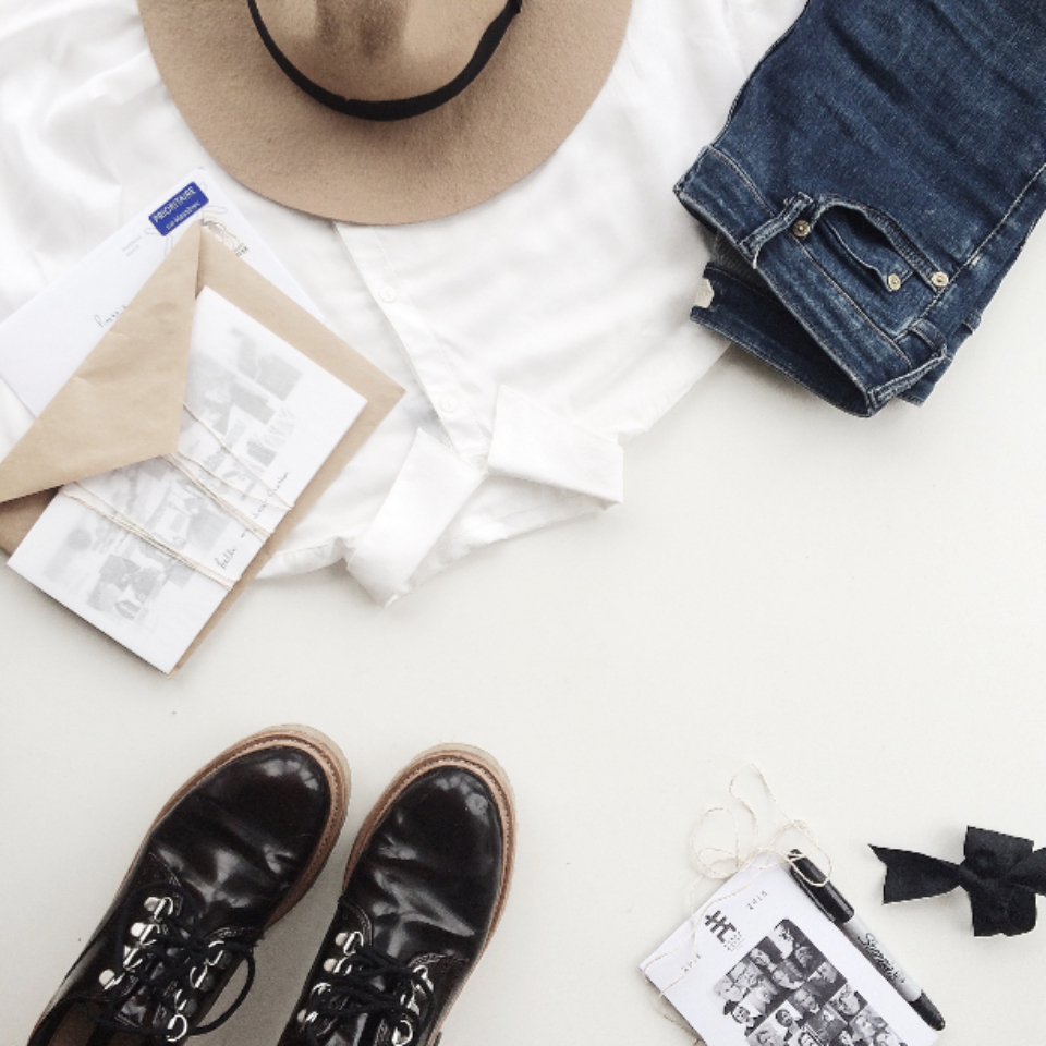 Flat lay of tan felt hat, white shirt, blue jeans, black boots, and stationery on white. — illustrating “OOTD Road Trip” on Florence and Mary