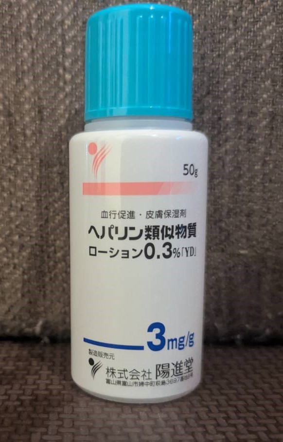 White plastic medicinal bottle with a bright blue cap and Japanese text on textured fabric. — illustrating “Palmer's Cocoa Butter Formula Intensive Hand Cream Review” on Florence and Mary