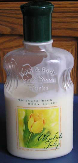 Clear bottle of white body lotion with a dark green cap and yellow tulip flower label. — illustrating “Palmers Cocoa Butter Natural Bronze Body Lotion” on Florence and Mary