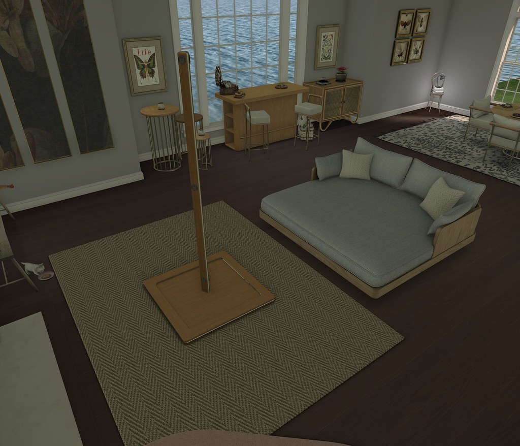 Modern living room with gray daybed, tall wooden pole on herringbone rug, and ocean-view windows. — illustrating “Products I used up in Ibiza” on Florence and Mary