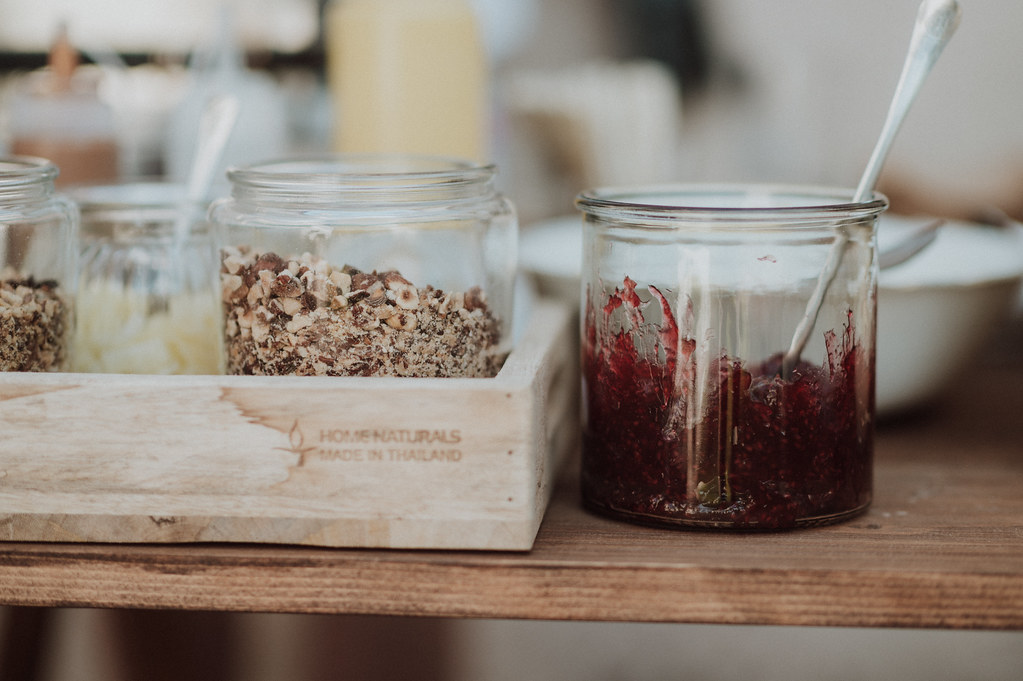 Glass jar of dark red jam with a spoon beside a wooden tray of chopped nuts in jars. — illustrating “Recipe // Sweet Potato & Chill Soup” on Florence and Mary