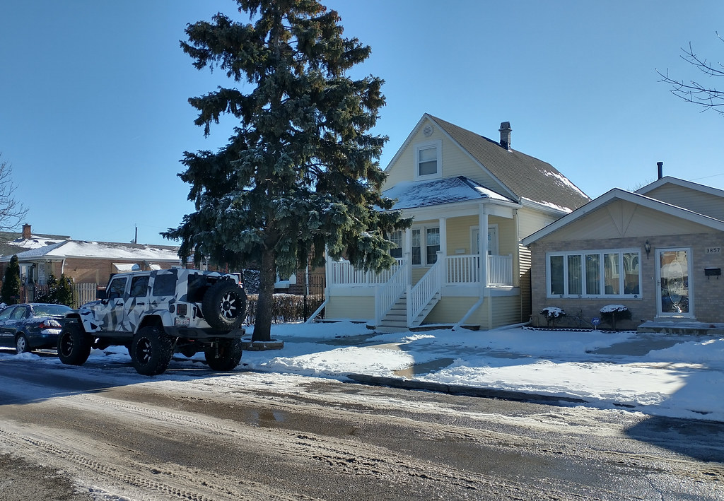 Camouflage-patterned SUV parked on snowy street before yellow house with white trim and large pine. — illustrating “The return of the Mad Men Season 6” on Florence and Mary