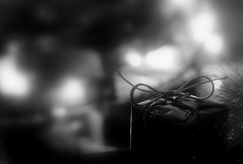 Black-and-white close-up of a small wrapped gift with string bow against blurry bokeh lights. — illustrating “CLOSED / US Drugstore Beauty Giveaway” on Florence and Mary