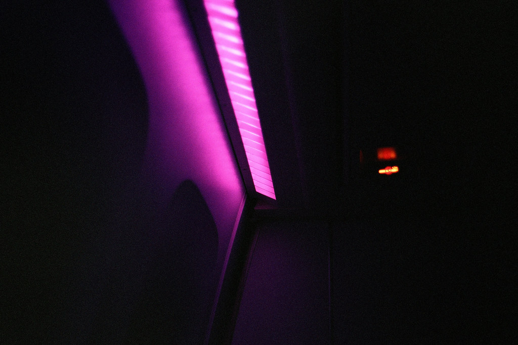 Vibrant pink light strip illuminating dark airplane cabin panels at night with a small red indicator. — illustrating “Virgin Atlantic Premium Economy - Is it worth it?” on Florence and Mary