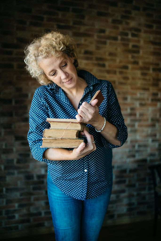 A curly blonde woman in a navy polka-dot shirt holds three vintage books against brick. — illustrating “Week 38 // What I'm Reading: Revenge Wears Prada” on Florence and Mary
