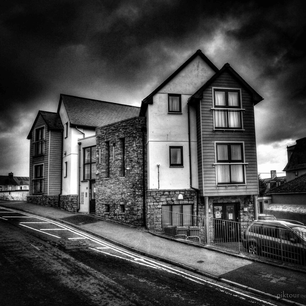 A black-and-white photo of a modern multi-story building on a sloped street under cloudy sky. — illustrating “What I got for Christmas 2013 | To Wear” on Florence and Mary