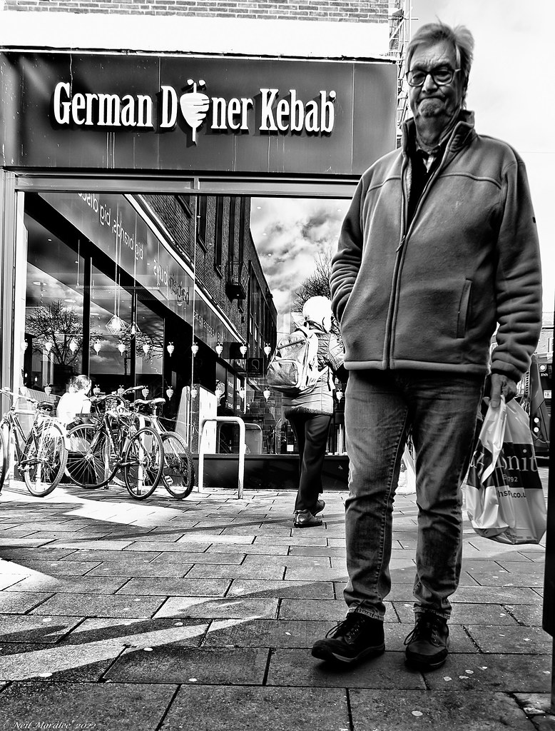 A black-and-white photo of an older man on a sidewalk outside a German Doner Kebab shop. — illustrating “What to buy when you have No 7 Vouchers” on Florence and Mary